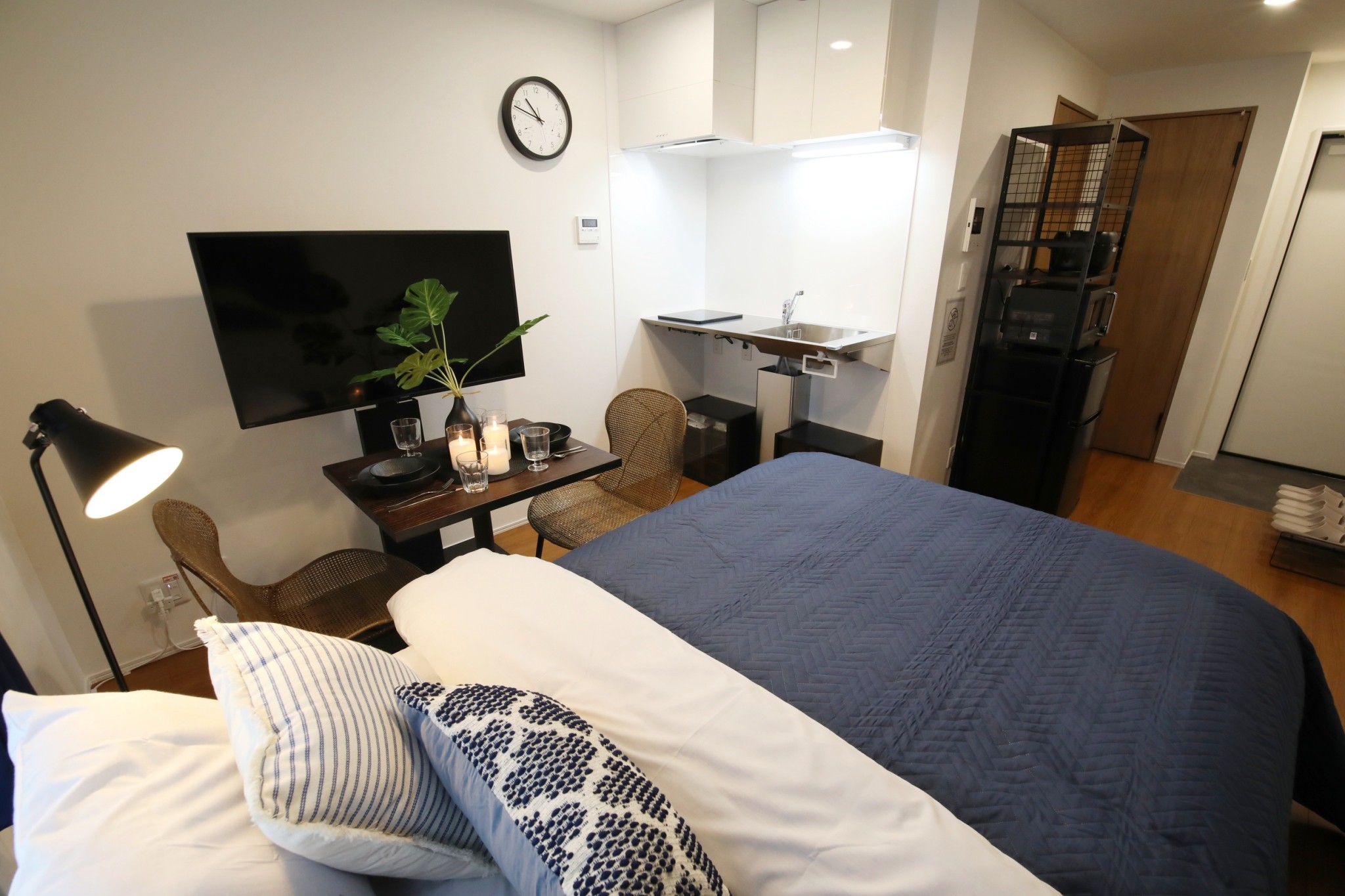 Room 202 LDK studio overview with navy bedding and wall-mounted TV