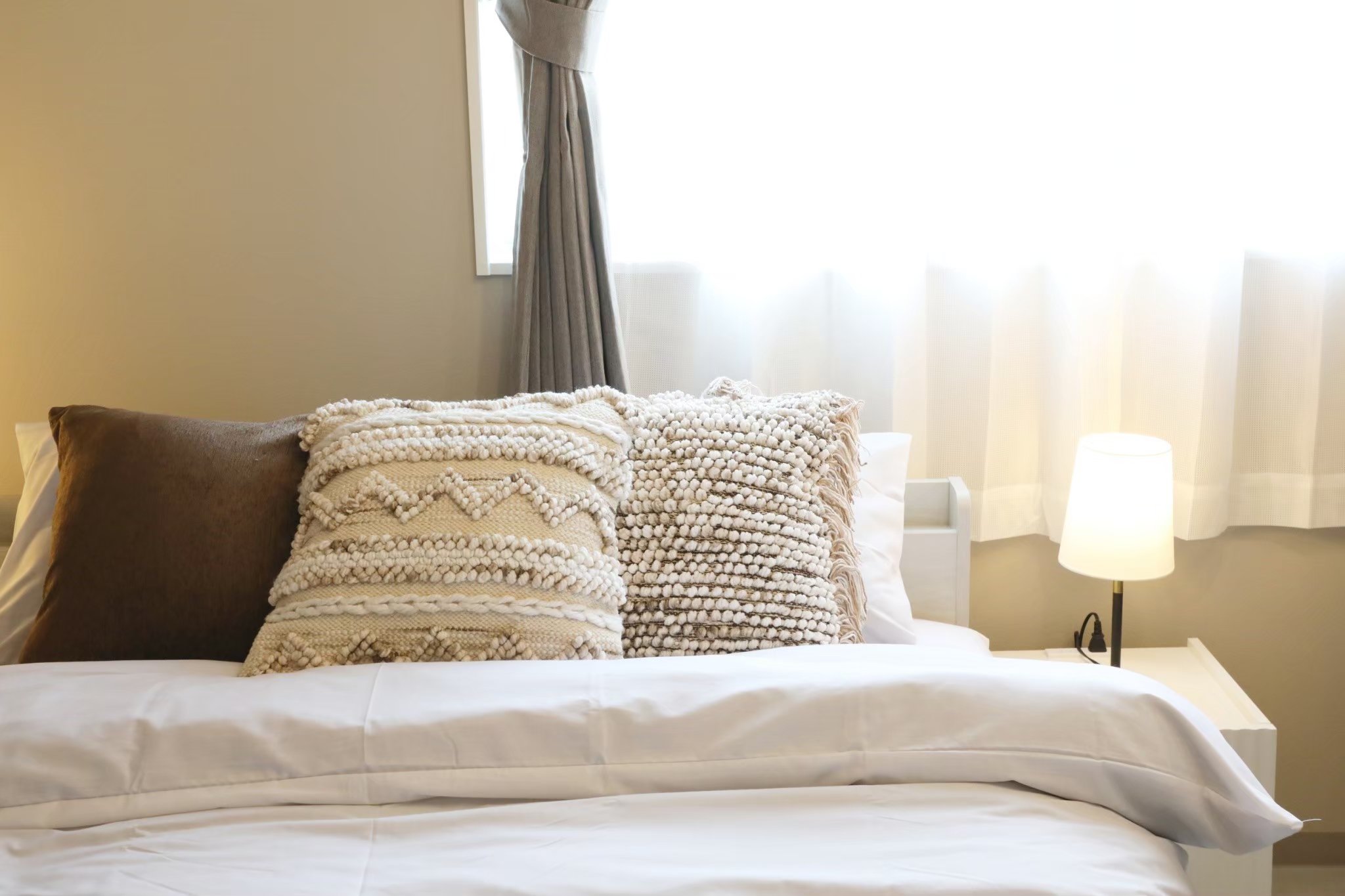Room 103 bed with textured pillows and warm morning light